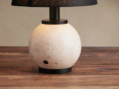 Celia Outdoor Rechargeable Lamp with creamy travertine spherical base, matte black hardware, and flax linen shade.