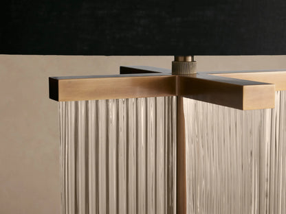Delsie Table Lamp: black cylindrical shade, fluted glass body with burnished brass accents, on a rustic wooden table.