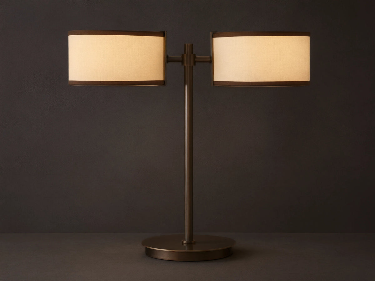 Daphne 2-Light Table Lamp with bronze-finished steel base and two cream shades with brown trim on a wooden surface.