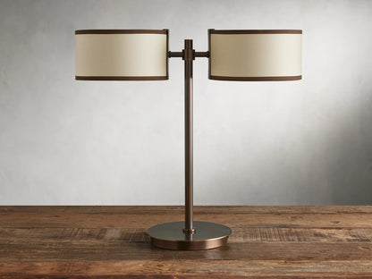 Daphne 2-Light Table Lamp with bronze-finished steel base and two cream shades with brown trim on a wooden surface.
