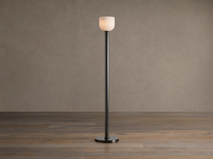 Ansley Floor Lamp: tall, dark steel pole and round base with an illuminated natural alabaster stone shade on a wooden floor.