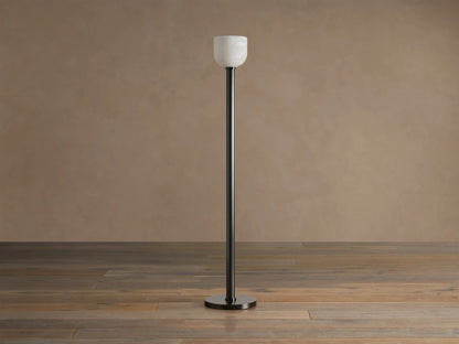 Ansley Floor Lamp: tall, dark steel pole and round base with an illuminated natural alabaster stone shade on a wooden floor.