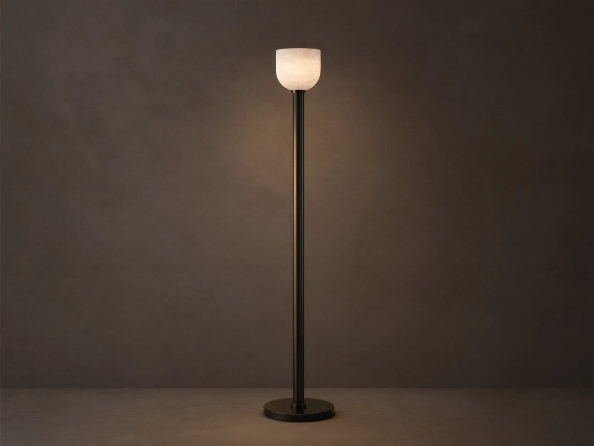 Ansley Floor Lamp: tall, dark steel pole and round base with an illuminated natural alabaster stone shade on a wooden floor.