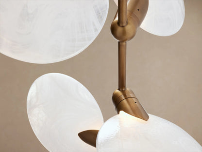 Lyla Floor Lamp: light travertine cone base, gold stem, and six white oval mouth-blown glass lights on wooden floor.