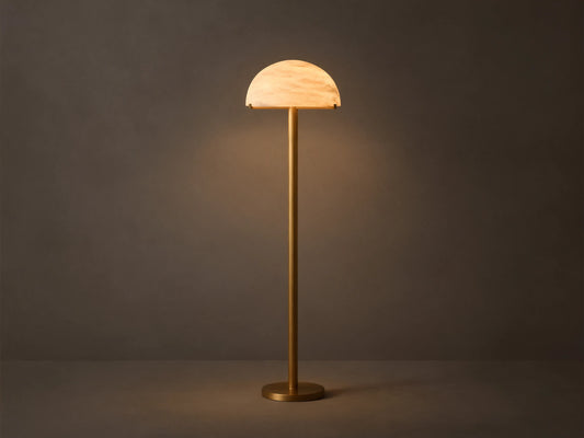 Front view of a brushed brass floor lamp with a half-dome mottled glass shade, emitting a warm glow.