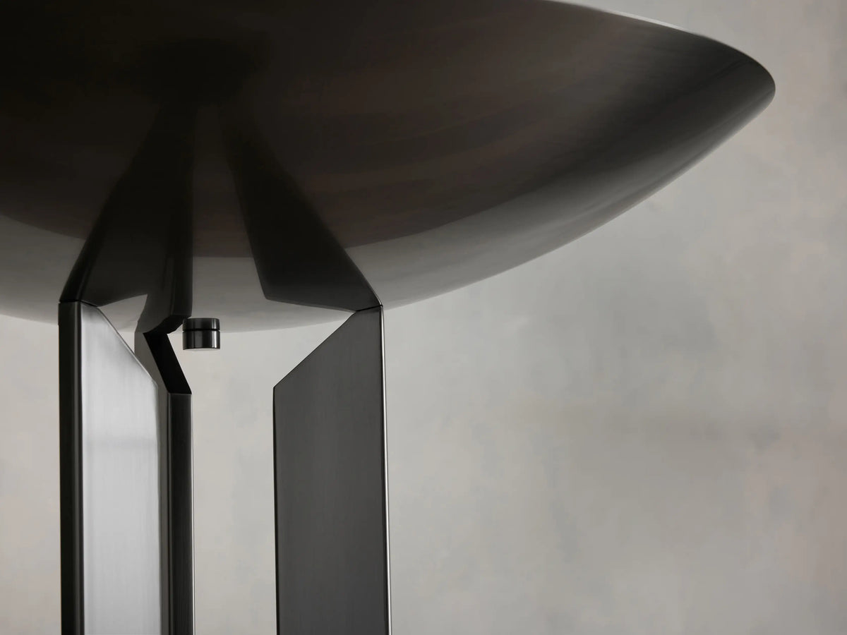 Close-up of Romina Floor Lamp's dark bronze conical shade underside & angular metal supports against a beige wall.