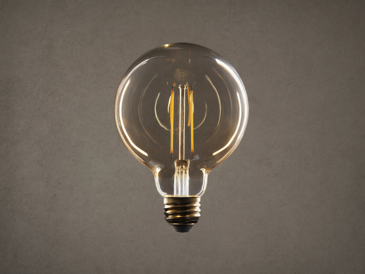Amber glass LED G30 filament bulb with E26 base, glowing with warm light against a black background, highlighting its round shape and two-line filament.