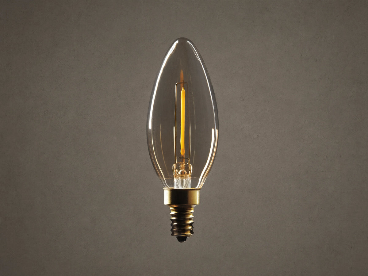 Amber glass LED B11 filament bulb with E12 base against black background. Bulb features a single visible filament and gold screw base.
