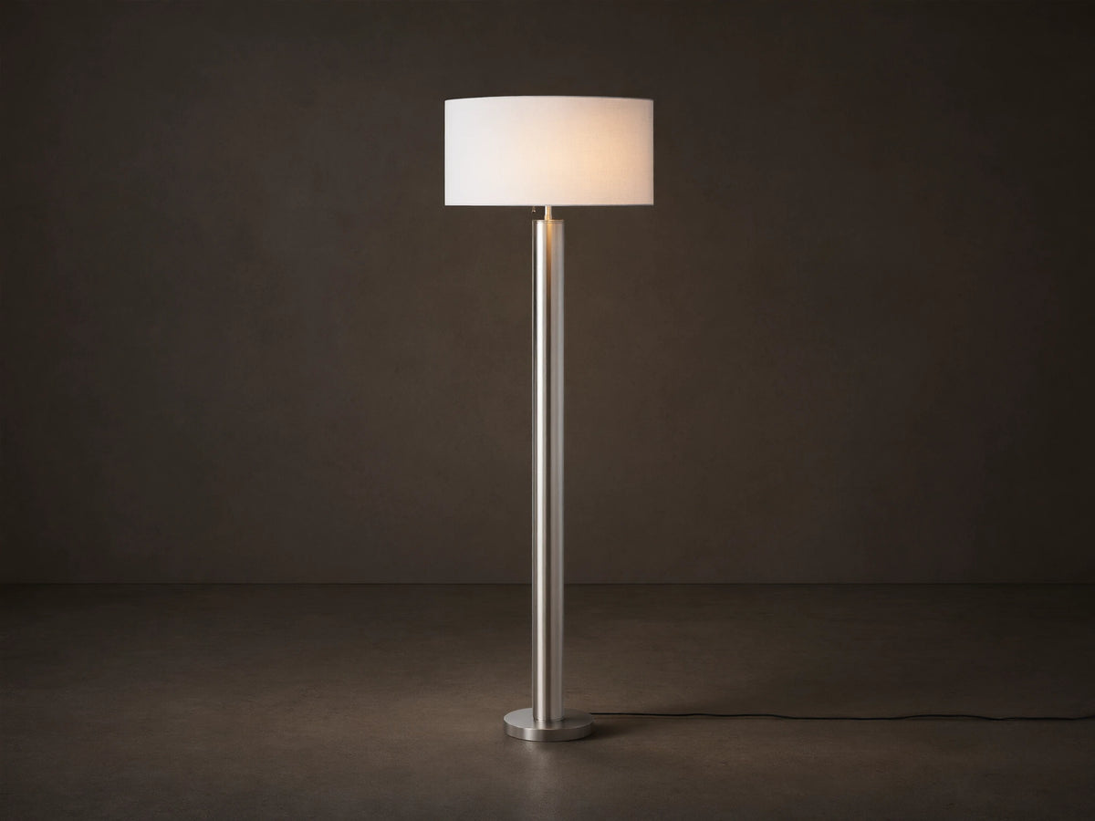 Linden Floor Lamp in Pewter: Tall, slender, metallic pewter finish pole and round base, with a white cylindrical linen shade.