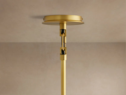 Linden Pendant with a light gray linen shade, viewed from below. Warm light illuminates the interior and a small brass-toned finial.