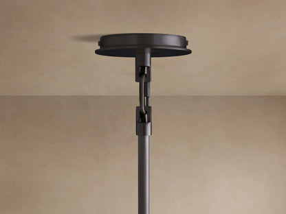 Linden Pendant with a light-colored, textured linen shade emitting warm light from its circular bottom. Black detail visible.