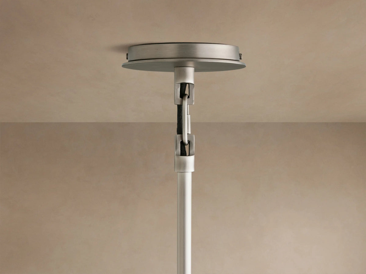 Close-up of a Linden Pendant, viewed from below, showing its light linen shade, warm interior glow, and dark metal accent.