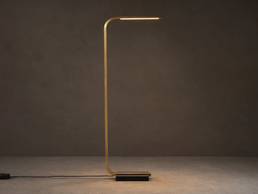 Modern brass Karson Task Floor Lamp with a curved stem, glowing light strip, and black marble base on a wood floor.