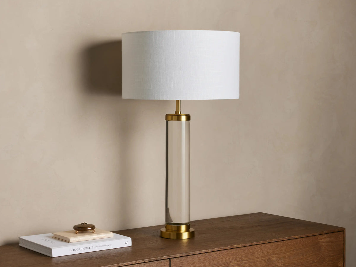 Close-up of the Linden Crystal Table Lamp, showing its light linen shade, brass-finished metal, and clear crystal column.