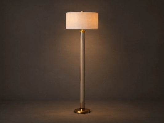 Linden Crystal Floor Lamp with clear column, brass accents, and an illuminated off-white linen shade, on a wood floor.