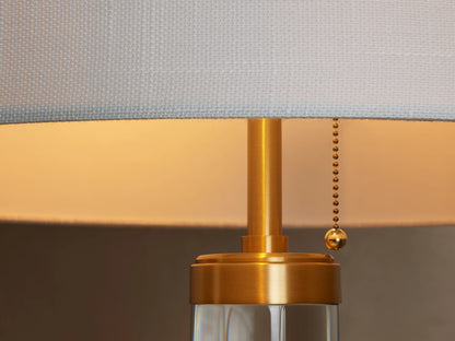 Linden Crystal Floor Lamp with a clear crystal column, brass accents, and a white linen drum shade, on a wooden floor.