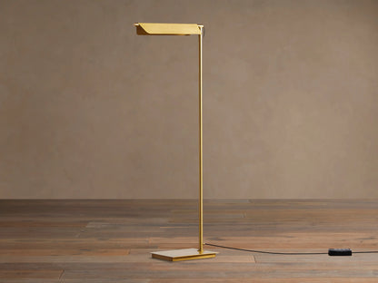 Close-up of Axle Brass Floor Lamp, showing its rectangular, pivoting shade and vertical pole in a brushed brass finish.