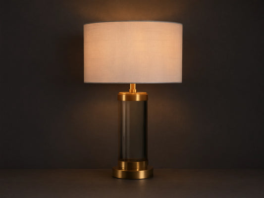 Linden Crystal Table Lamp with clear crystal column, brass accents, and off-white linen shade, glowing on a wooden table.