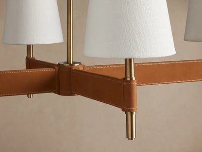 Hastings Linear Chandelier: 6 white linen shades on an antiqued brass & tan leather horizontal bar, suspended.