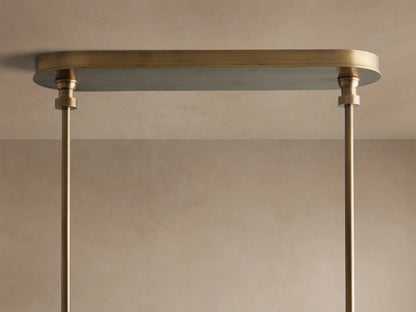 Close-up of Hastings Linear Chandelier, showing brass, brown leather straps with white stitching, and white linen shades.