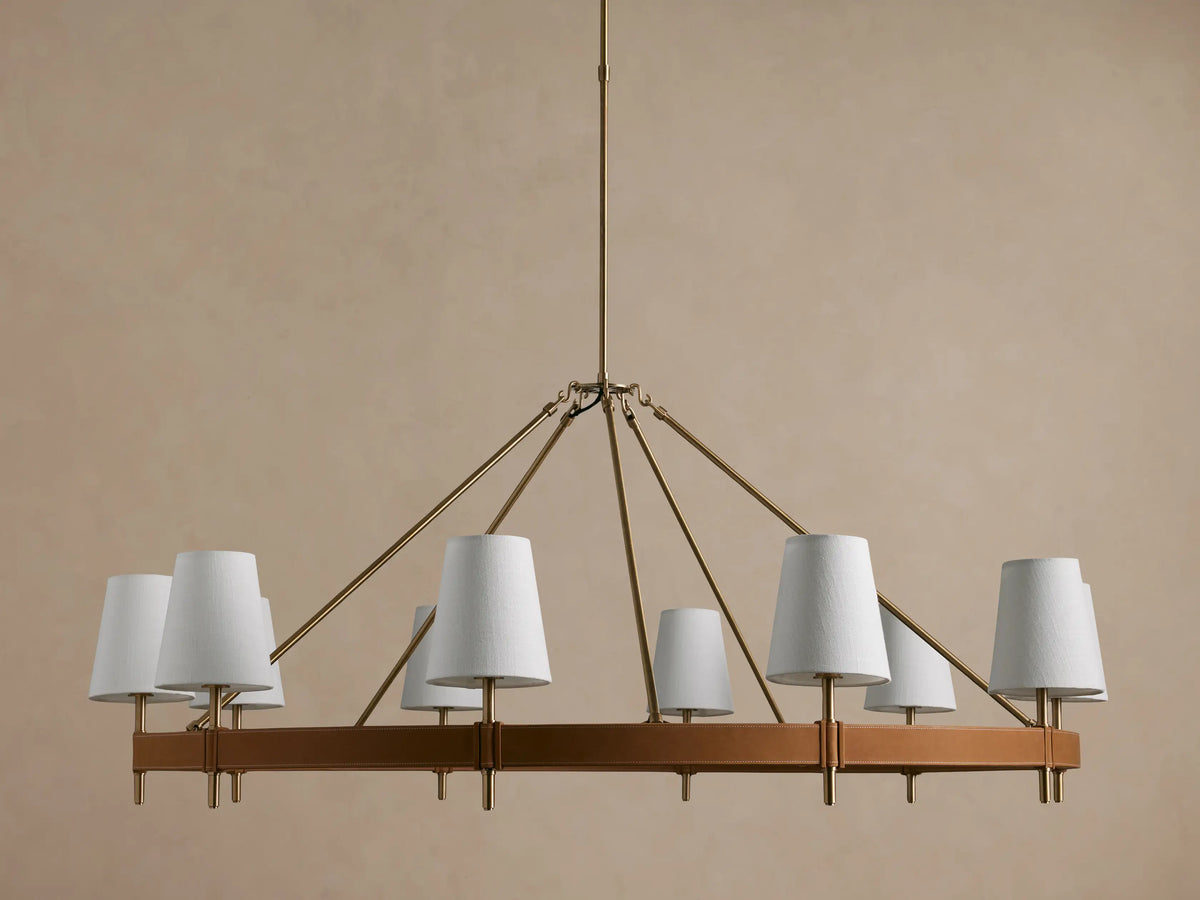 Hastings Round Chandelier, antiqued brass frame with brown leather, and 8 glowing white linen shades.