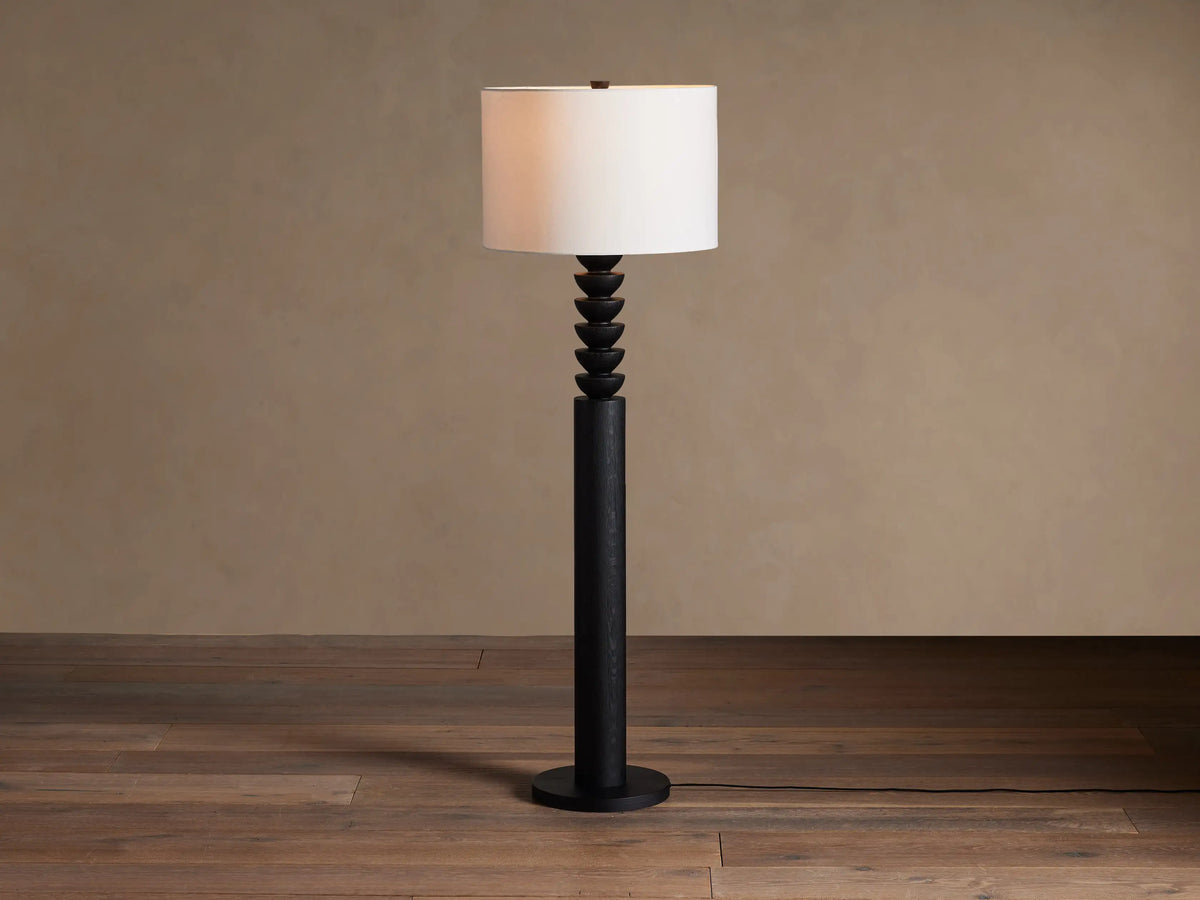 Black Lathe Floor Lamp with a cylindrical black oak base, stacked carved black wood details, and an off-white linen drum shade.