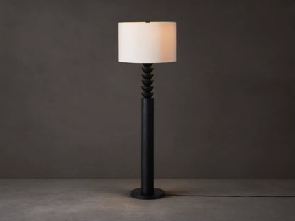Black Lathe Floor Lamp with a cylindrical black oak base, stacked carved black wood details, and an off-white linen drum shade.