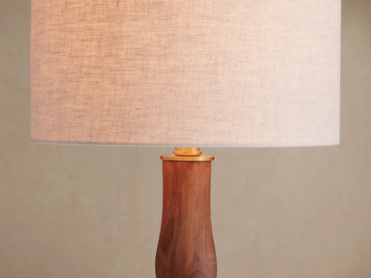 Jonas Table Lamp with light flax linen shade and dark twisted oak wood base, brass accents, on a rustic wooden table.