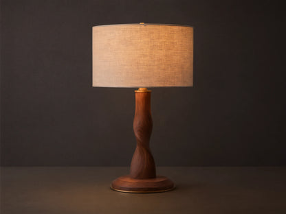 Jonas Table Lamp with a light flax linen shade, twisted dark oak wood base, and brass accents, sitting on a rustic wooden table.