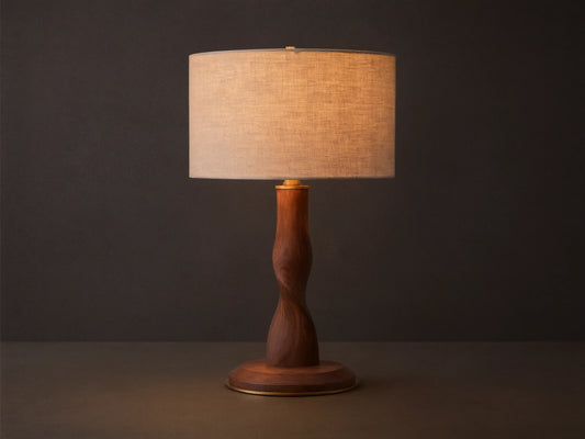 Jonas Table Lamp with a light flax linen shade, twisted dark oak wood base, and brass accents, sitting on a rustic wooden table.