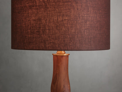 Jonas Table Lamp with a dark brown linen shade and twisted oak wood base, finished with brass accents, on a wooden surface.