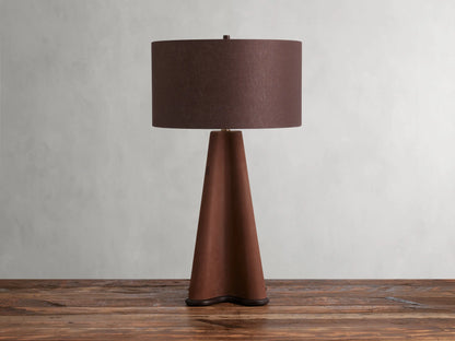 Volant Table Lamp with cone-shaped oak wood base, brass accents, and brown linen shade on a wooden surface.