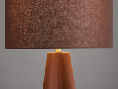 Volant Table Lamp with a conical oak wood base, brown linen shade, and brass accents, on a wooden surface.