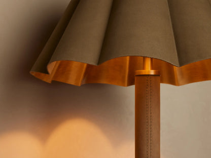 Close-up of Lucy Accent Table Lamp with pleated brown shade, golden interior, and brown leather-wrapped stem. Warm glow.