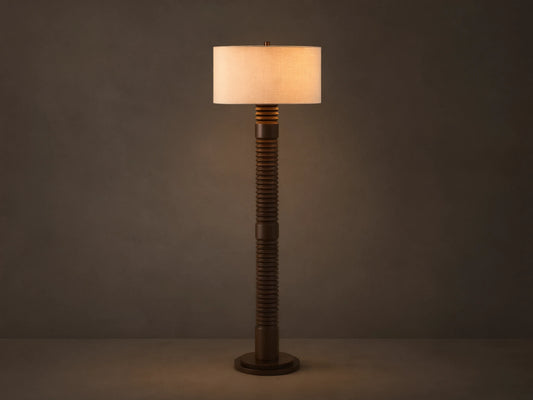 Front view of a dark brown ribbed floor lamp with a cylindrical beige fabric shade, emitting a warm glow.