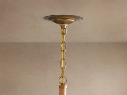 Ravda Round Chandelier's brass ceiling plate, chain, & gold cord hanging from a light beige ceiling.