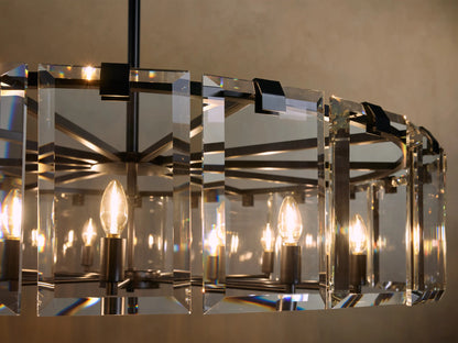 A rectangular chandelier with black metal frame features multiple candle-like bulbs surrounded by clear, faceted crystal panels emitting warm light.