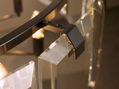 Close-up view of a modern chandelier featuring clear glass panels and a metal frame with a dark finish, illuminated by warm lights.