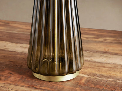 Elisabetta Table Lamp with a dark fluted glass conical base, brass-finish bottom, and white linen shade on a wood table.