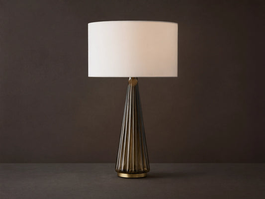 Elisabetta Table Lamp: upright, white linen shade, smoky fluted glass base, brass accent, sitting on a wooden table.