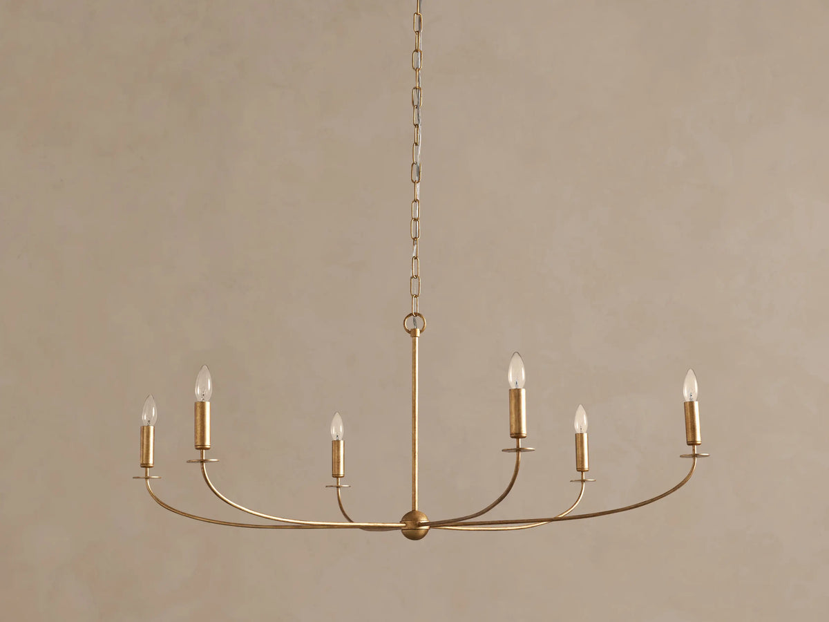 Arnett Chandelier: An antiqued gold 6-light chandelier hangs centrally, featuring curved arms with clear candle-style bulbs.