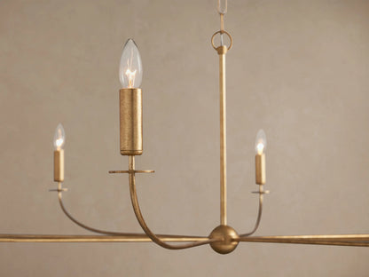 Arnett Chandelier close-up: antiqued golden iron frame, curved arms, and three illuminated candle-style bulbs.