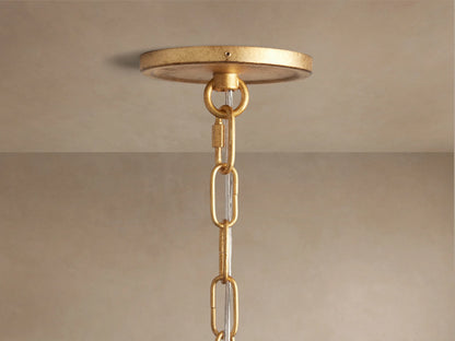 Close-up of Arnett Chandelier's round antiqued golden ceiling canopy and top chain links with clear cord against a beige ceiling.