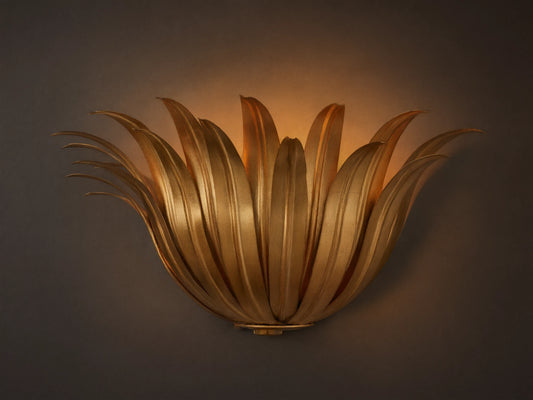 Matilde Sconce, an antique-gold iron wall light resembling layered leaves, casting a warm glow on a neutral wall.
