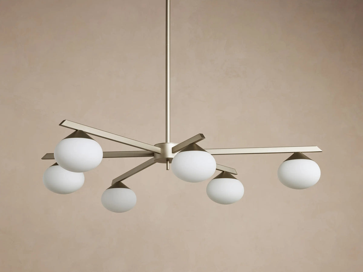 Costella Round Chandelier with six illuminated opal glass globe diffusers on champagne finish iron arms, hanging from above.