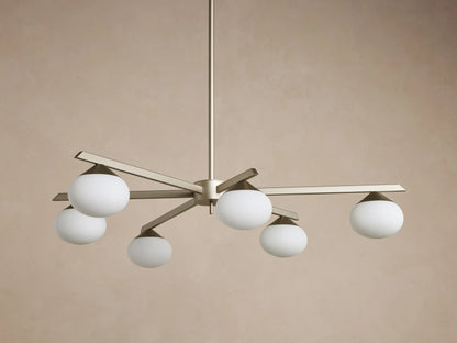 Costella Round Chandelier with six illuminated opal glass globe diffusers on champagne finish iron arms, hanging from above.