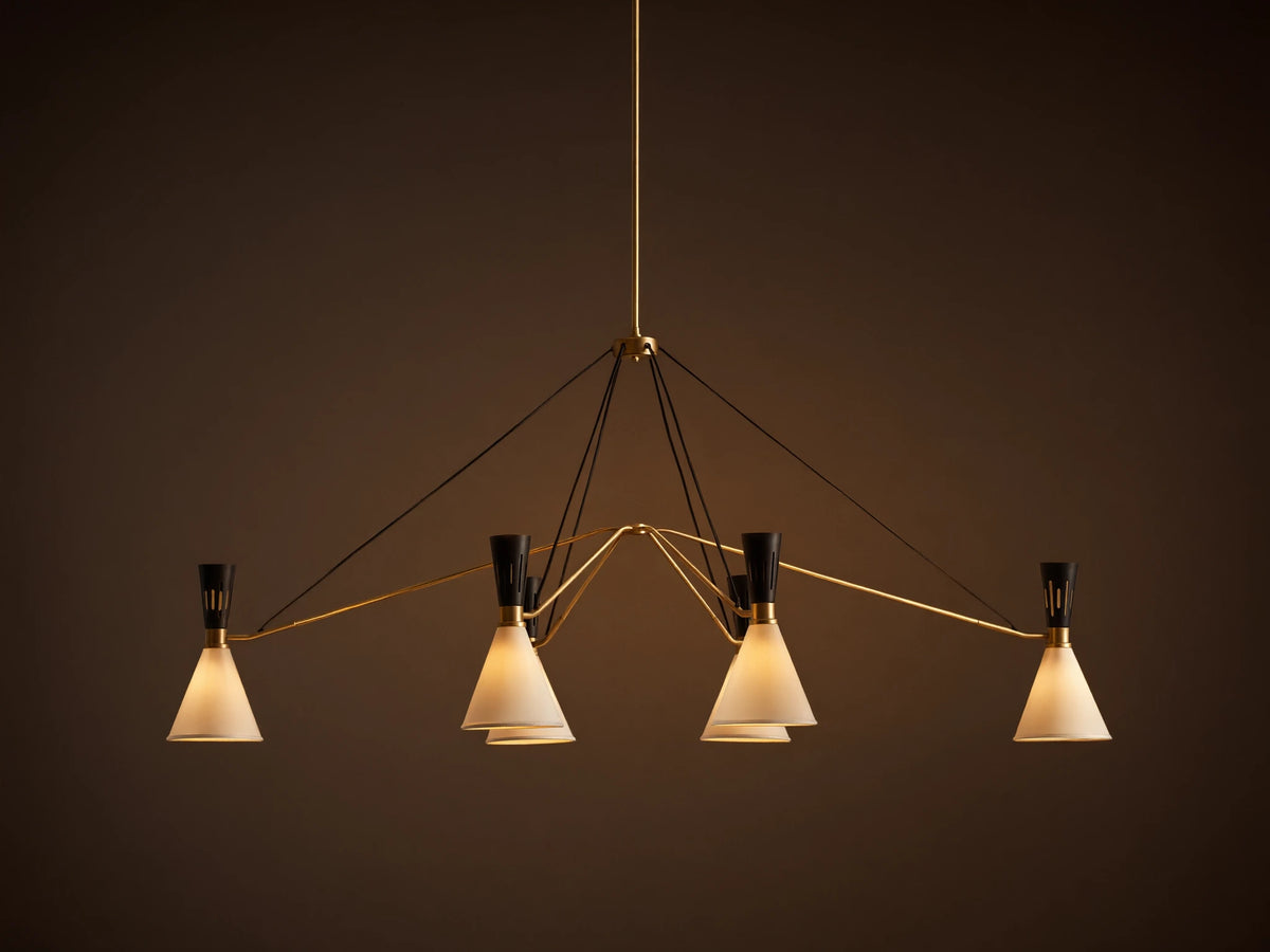 Ramsey Linear Chandelier with a satin brass frame, matte black accents, and six glowing white conical fabric shades.