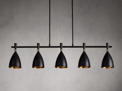 Jacarra Linear Chandelier with five black metal shades, gold leaf interior, hanging from an old bronze rod against a gray background.