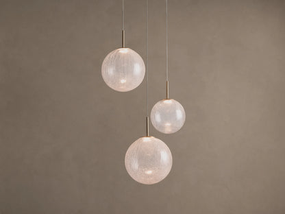 Casen Round Chandelier. Three illuminated crackle glass globes with satin brass accents, suspended at varying heights.