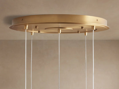 Close-up of Casen Round Chandelier's satin brass ceiling mount, with several thin white suspension cables descending.